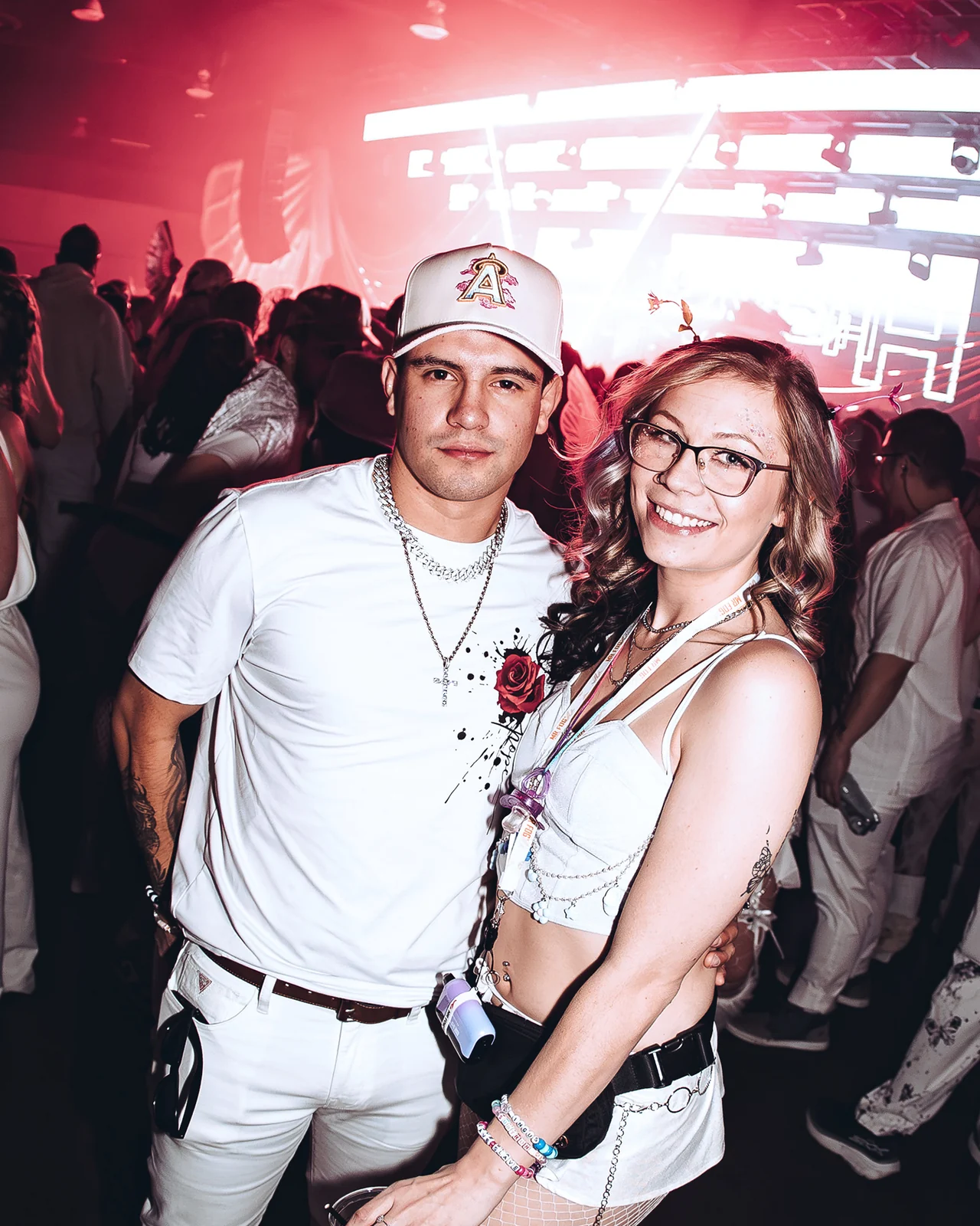 A couple dressed head to toe in white under pink stage light