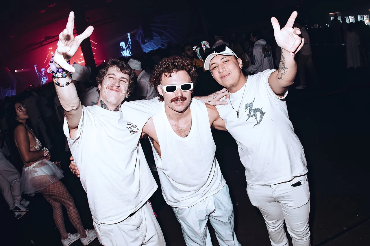 Three guests in white flashing peace signs on the dancefloor