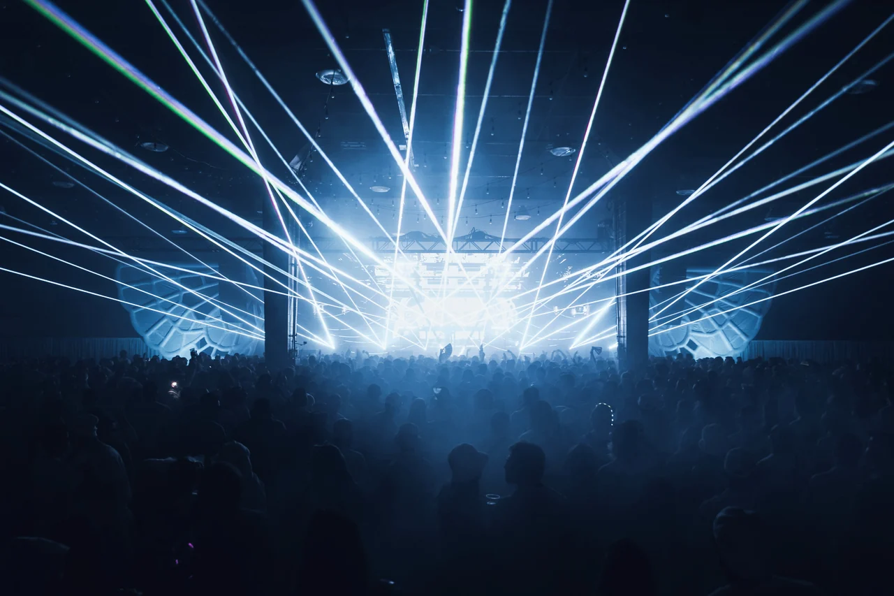 White laser beams bursting over the darkened crowd