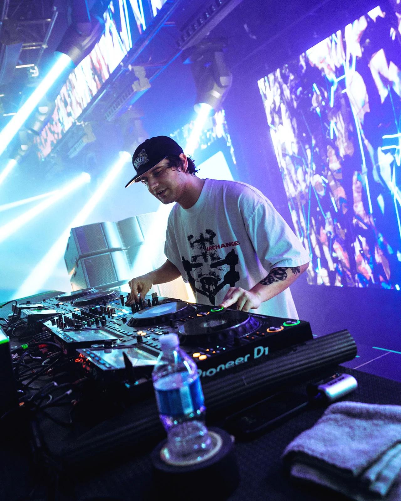 A DJ performing at the decks in front of a purple LED wall
