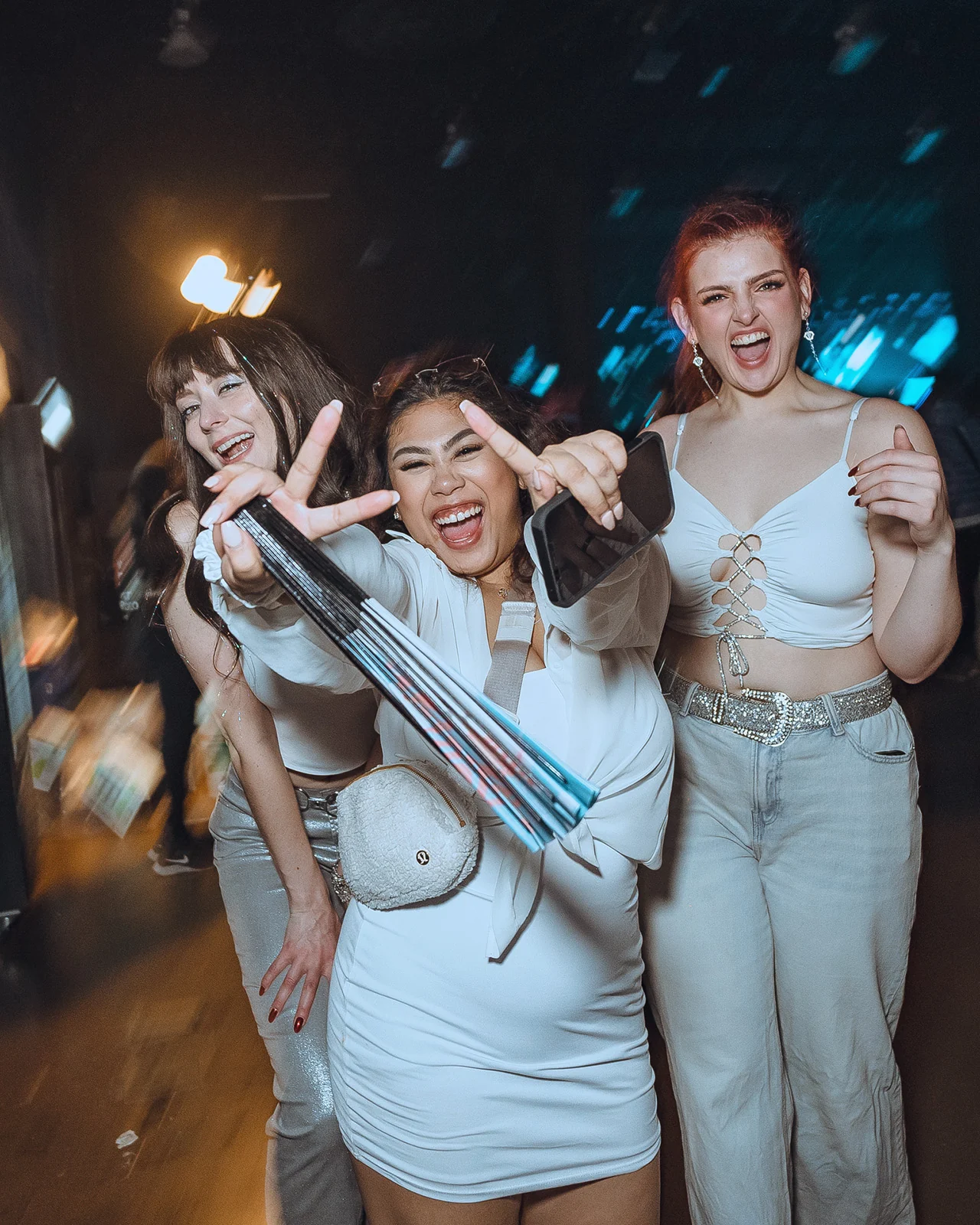 Two guests in white making peace signs at PURE 2024