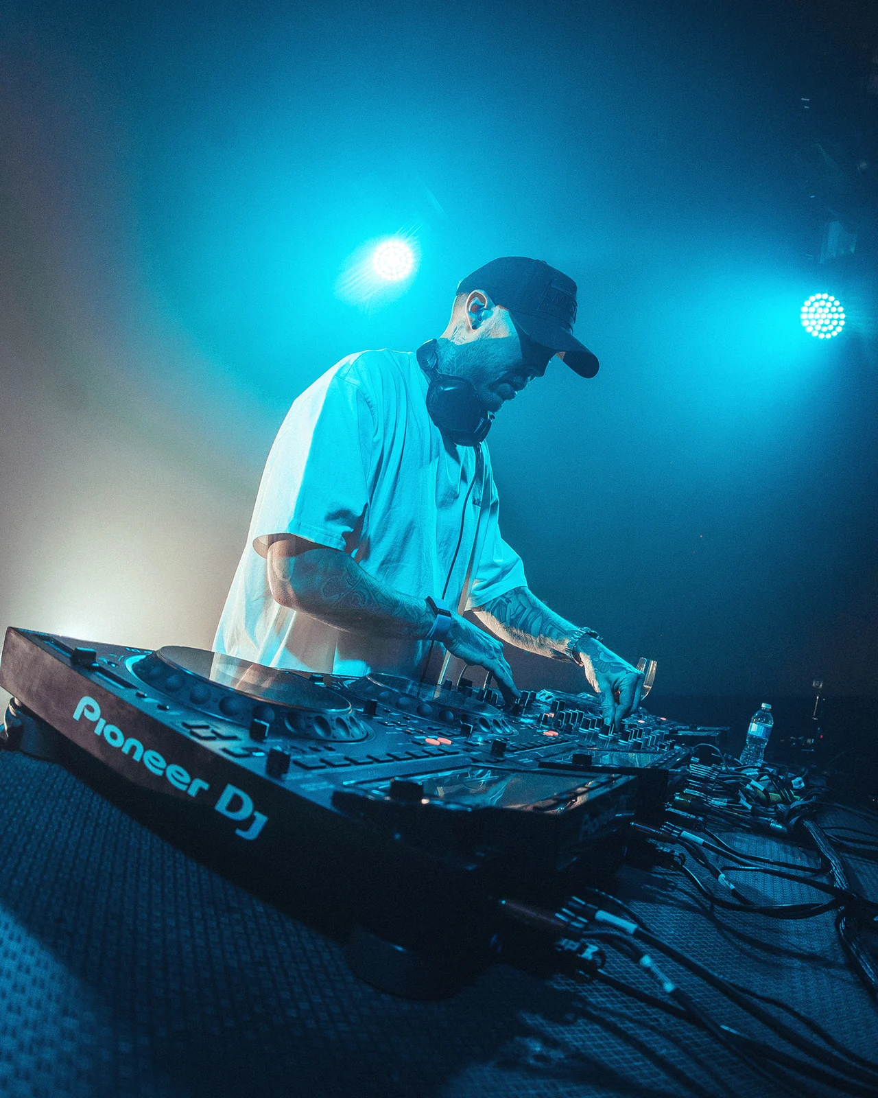A DJ silhouetted in blue haze behind the decks