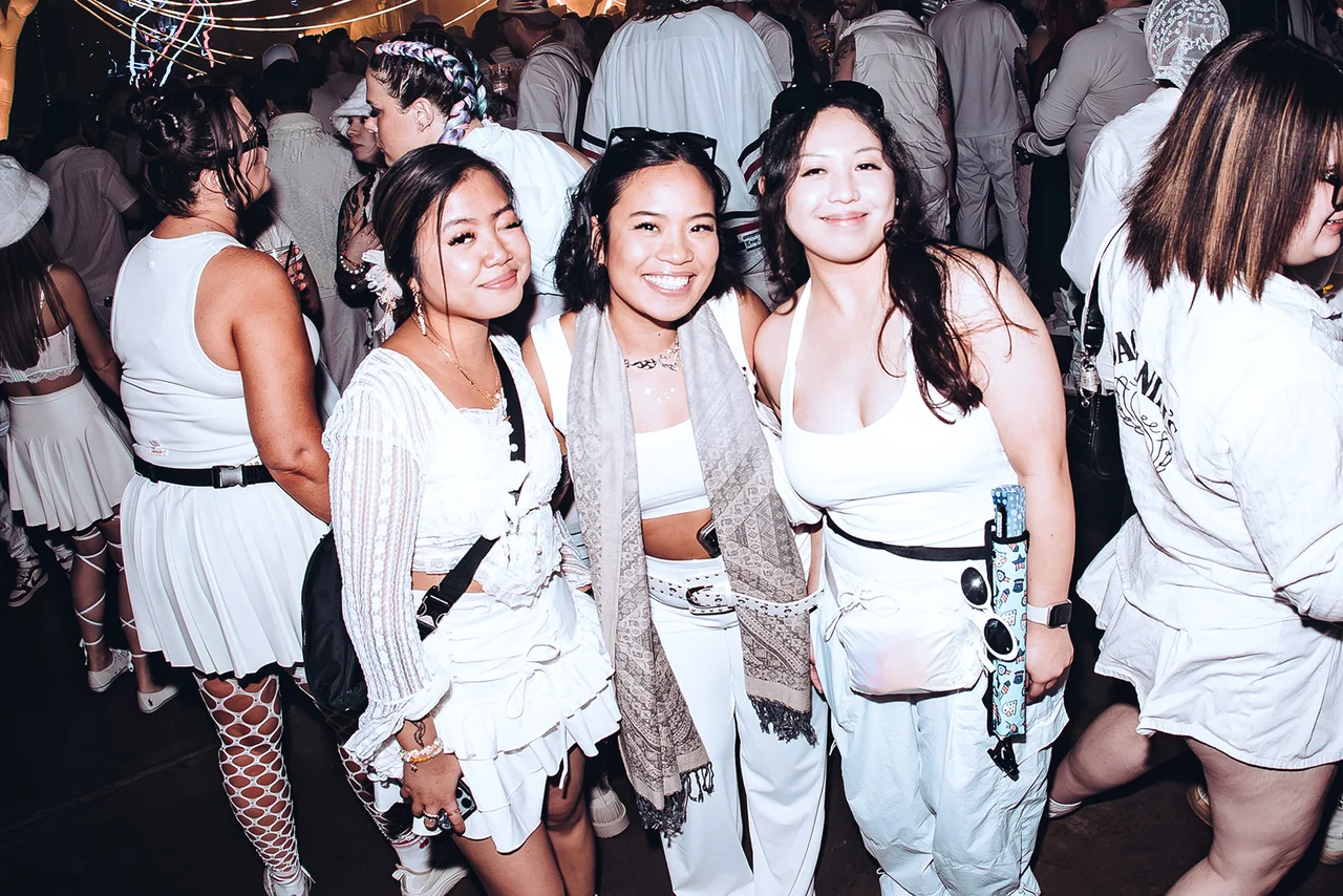 Friends in all-white outfits posing together at PURE 2025
